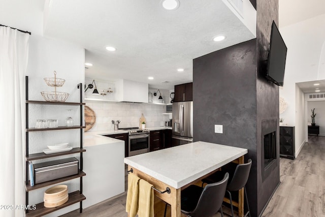 kitchen featuring recessed lighting, appliances with stainless steel finishes, light countertops, light wood finished floors, and a peninsula