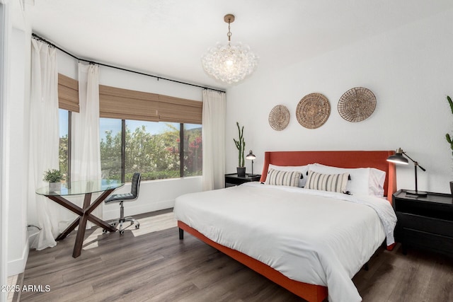bedroom featuring baseboards, wood finished floors, and a notable chandelier