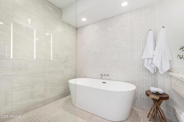full bathroom featuring walk in shower, recessed lighting, tile walls, and a freestanding tub