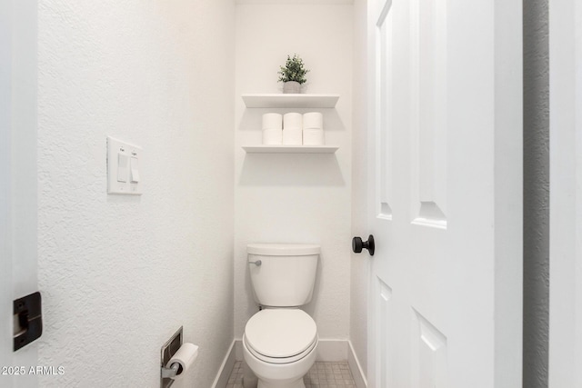 bathroom with baseboards, tile patterned floors, and toilet