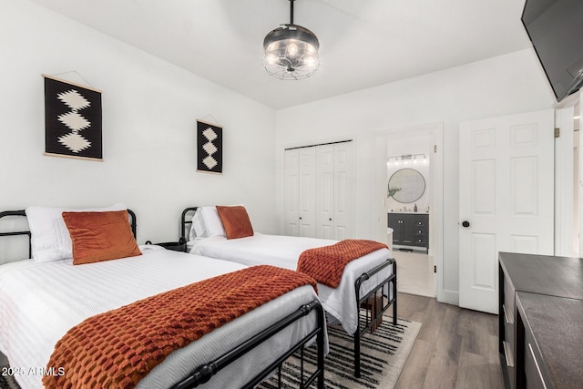 bedroom with connected bathroom, a closet, and wood finished floors