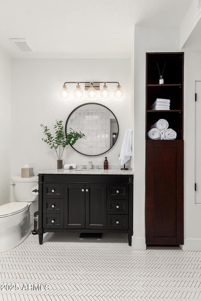bathroom featuring baseboards, visible vents, toilet, and vanity