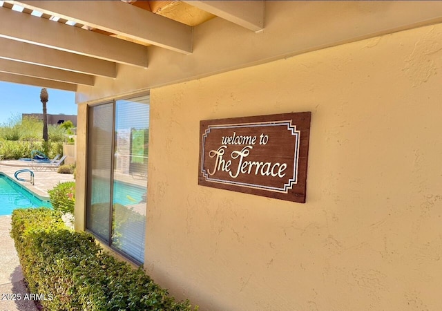 exterior details with stucco siding and a swimming pool