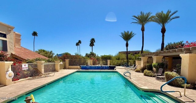 community pool with a patio and fence