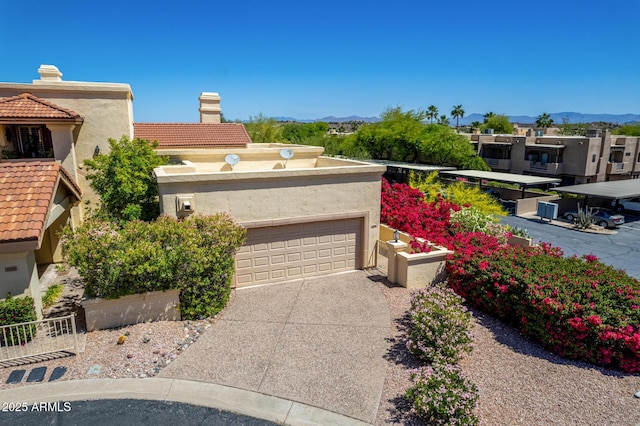 view of front facade with a chimney, a mountain view, concrete driveway, and an attached garage