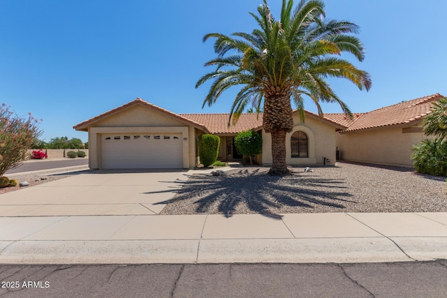 view of front facade featuring a garage, stucco siding, concrete driveway, and a tile roof