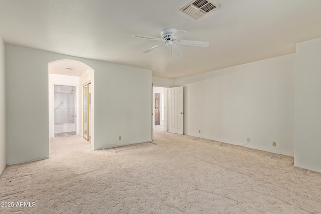 empty room featuring visible vents, arched walkways, ceiling fan, and carpet flooring