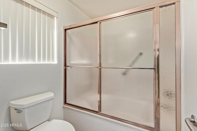 bathroom with toilet and bath / shower combo with glass door