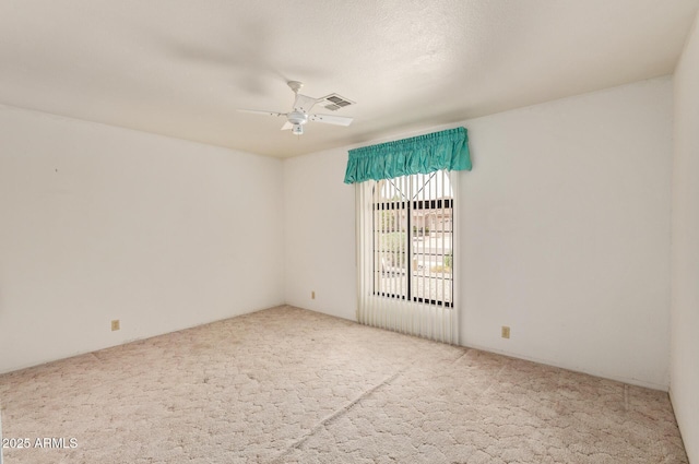 spare room featuring carpet floors, a ceiling fan, and visible vents