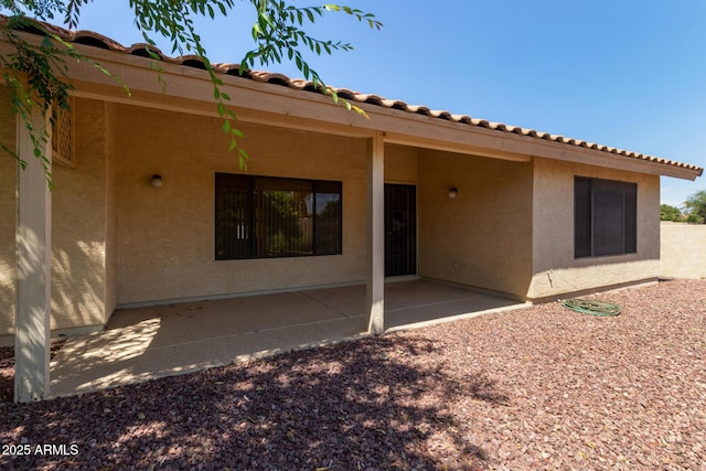 rear view of property with a patio area, stucco siding, and a tiled roof