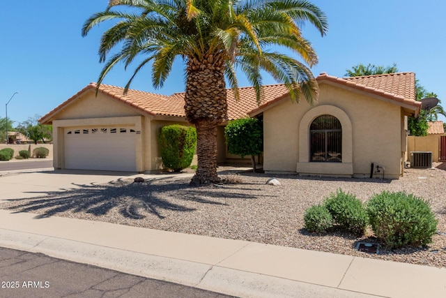 mediterranean / spanish home featuring a garage, driveway, central AC, and stucco siding