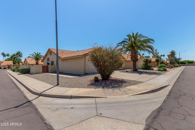 view of front facade featuring a garage, fence, stucco siding, driveway, and a tile roof