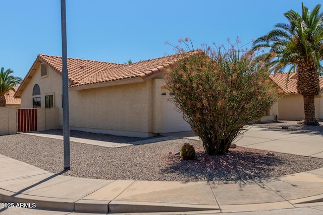 view of front of home with fence, an attached garage, a tile roof, and stucco siding
