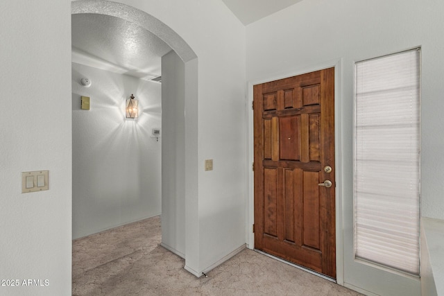 entryway with arched walkways and light carpet