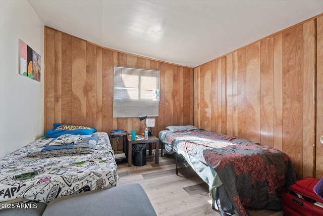 bedroom featuring light hardwood / wood-style floors and wood walls