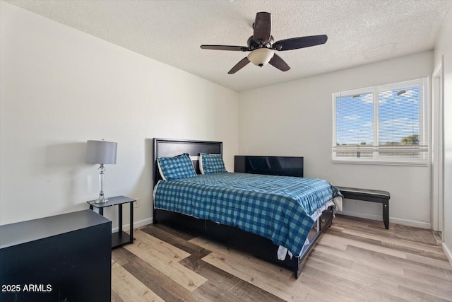 bedroom featuring ceiling fan, a textured ceiling, and light wood-type flooring