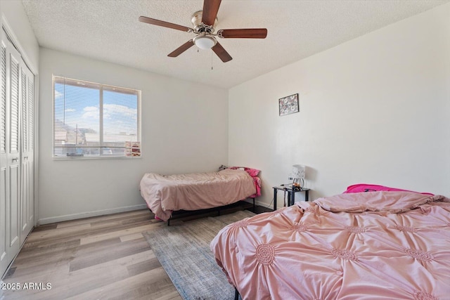 bedroom with a textured ceiling, a closet, light hardwood / wood-style floors, and ceiling fan