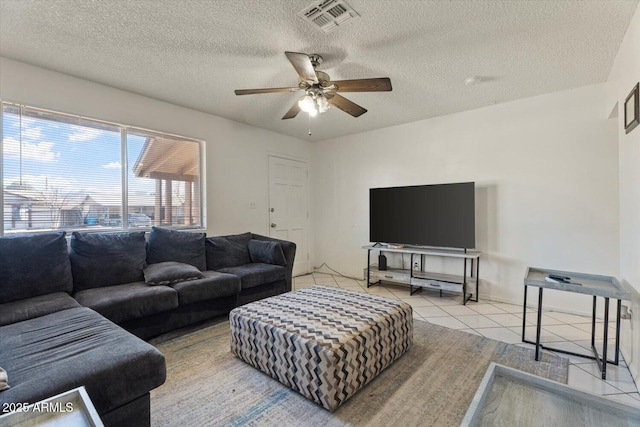 living room with a textured ceiling, ceiling fan, and light tile patterned flooring