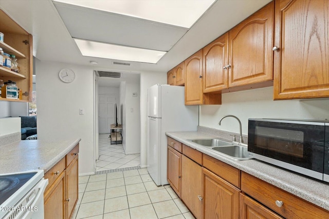 kitchen featuring light tile patterned floors, sink, white refrigerator, and range