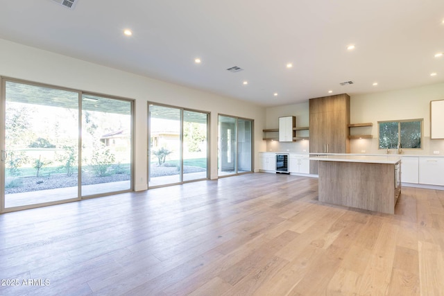 kitchen featuring white cabinets, light hardwood / wood-style floors, a center island, and wine cooler