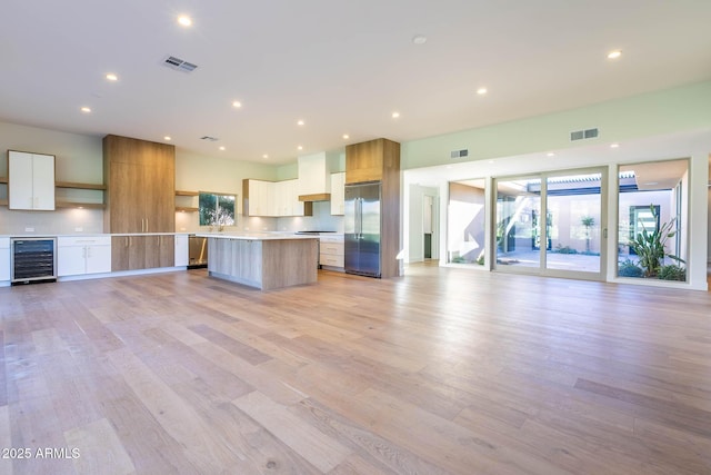 kitchen featuring light hardwood / wood-style flooring, a kitchen island, beverage cooler, built in fridge, and white cabinetry