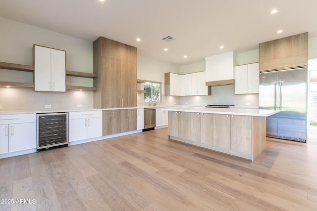 kitchen with a kitchen island, white cabinets, wine cooler, and appliances with stainless steel finishes