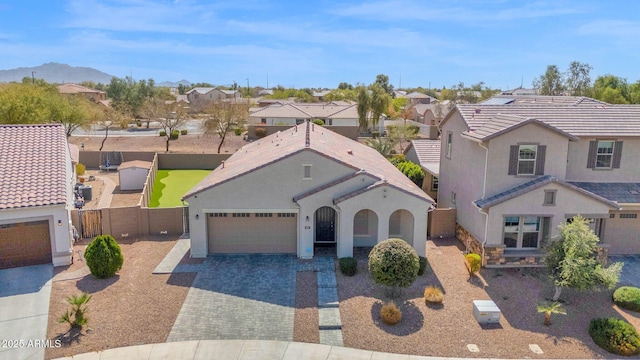 view of front facade with a residential view, a tile roof, decorative driveway, and a garage