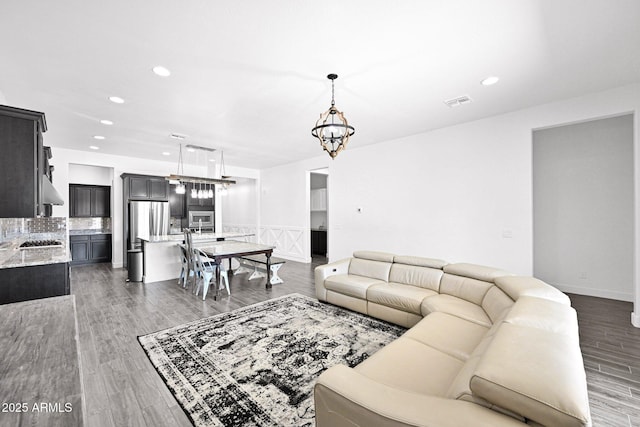 living room featuring recessed lighting, visible vents, a notable chandelier, and light wood-style flooring