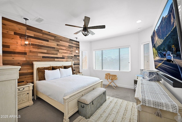 bedroom featuring visible vents, a ceiling fan, wooden walls, carpet flooring, and baseboards