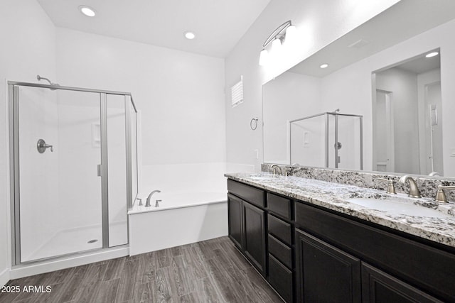 full bathroom featuring a shower stall, a garden tub, wood finished floors, and a sink