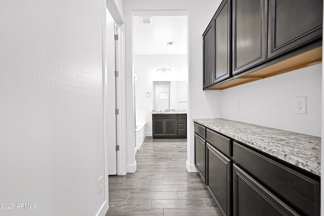 corridor with wood finished floors, visible vents, and baseboards