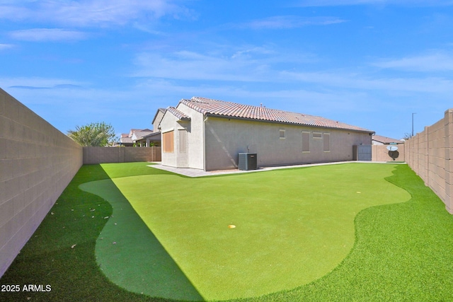 back of property featuring stucco siding, central air condition unit, a fenced backyard, and a tiled roof