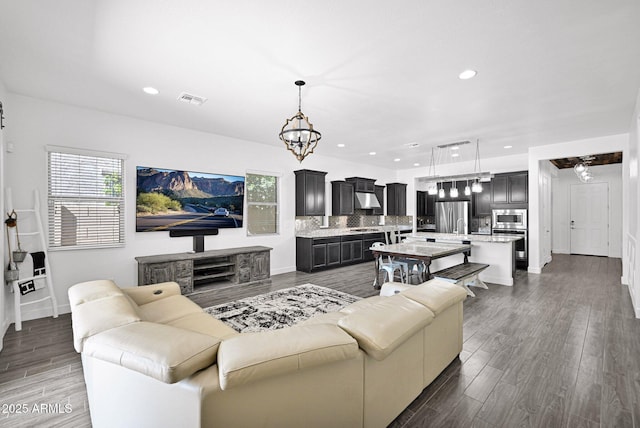 living room with dark wood finished floors, visible vents, recessed lighting, and a notable chandelier