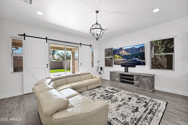 living area with recessed lighting, baseboards, a barn door, and wood finished floors