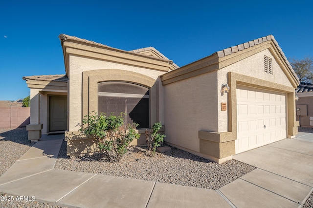 view of front facade featuring a tile roof, stucco siding, driveway, and an attached garage