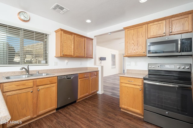 kitchen featuring visible vents, a sink, light countertops, appliances with stainless steel finishes, and dark wood-style flooring