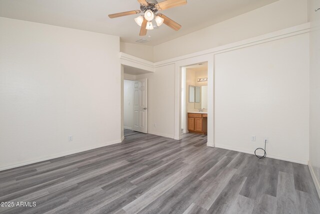 unfurnished bedroom with a ceiling fan, ensuite bathroom, a sink, dark wood finished floors, and baseboards