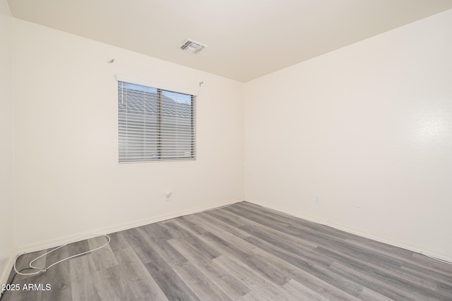 unfurnished room with visible vents, baseboards, and wood finished floors