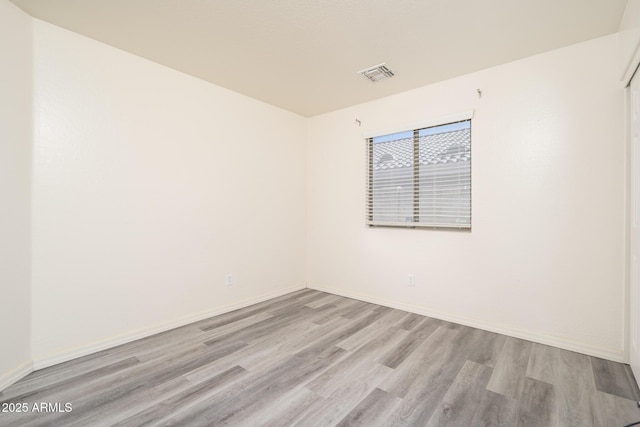 empty room with visible vents, baseboards, and wood finished floors