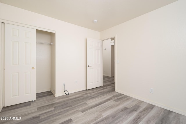 unfurnished bedroom with a closet, baseboards, and wood finished floors