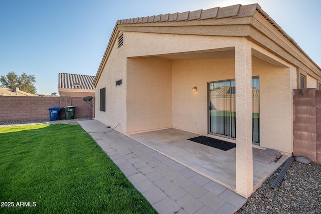 back of property with a patio area, stucco siding, a lawn, and fence