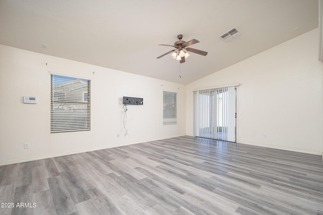 empty room with lofted ceiling, visible vents, light wood-type flooring, and ceiling fan