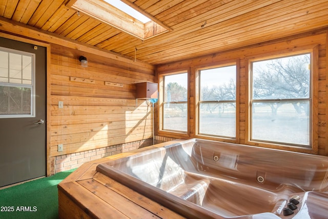 bathroom with wood ceiling, plenty of natural light, a skylight, and a bathtub