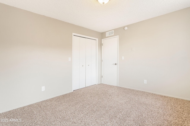 unfurnished bedroom featuring carpet floors, a textured ceiling, and a closet