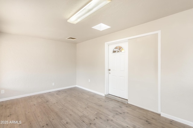 empty room featuring hardwood / wood-style flooring and a skylight