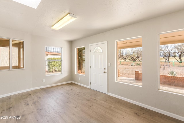 entrance foyer with hardwood / wood-style floors, plenty of natural light, and a skylight