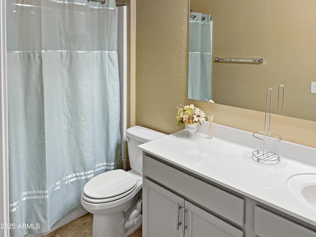 bathroom featuring tile patterned flooring, vanity, toilet, and walk in shower