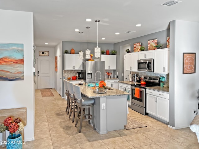 kitchen featuring sink, an island with sink, tasteful backsplash, white cabinetry, and stainless steel appliances