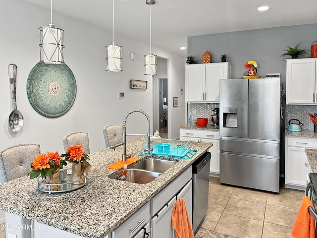 kitchen with white cabinets, sink, decorative backsplash, an island with sink, and stainless steel appliances