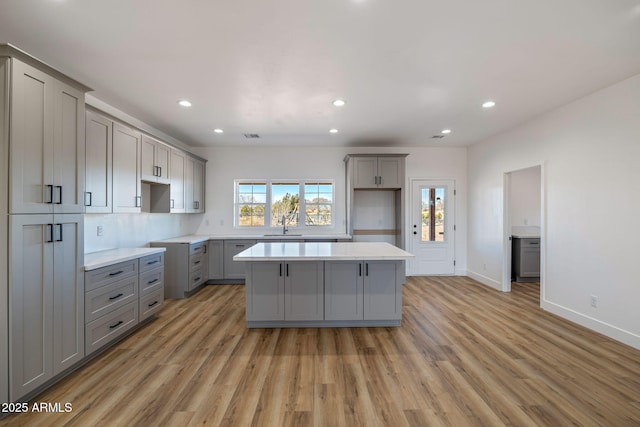 kitchen featuring a kitchen island, sink, gray cabinetry, and light hardwood / wood-style floors